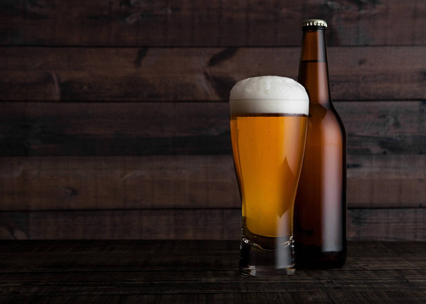 Glass and bottle of golden lager beer with foam  - Foto, Bild