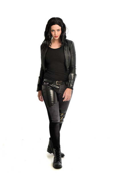 retrato de comprimento total da menina de cabelos pretos vestindo roupa de couro. postura em pé sobre um fundo branco
. - Foto, Imagem
