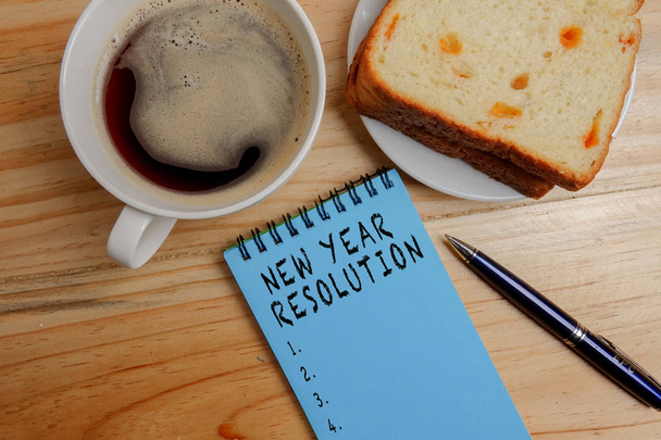 Neujahrsauflösung: Notizblock und Kaffeetasse leer auf Holztisch im Büro - Foto, Bild