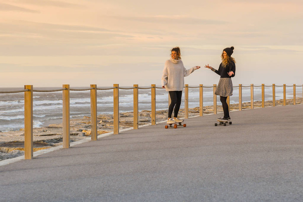 Two female friends playing with skateboard  - 写真・画像