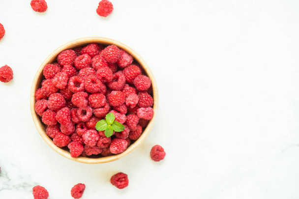 Red raspberries fruit in wood bowl on table - Fotó, kép