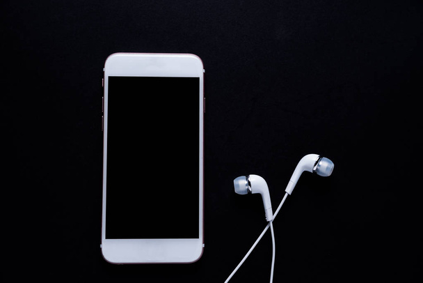 Mobile phone with earphone on dark background - Photo, Image