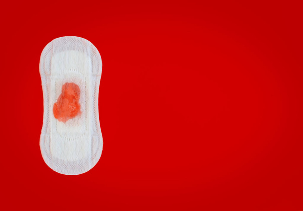 Feminine sanitary napkin with red liquid drops on red background - Foto, Imagem