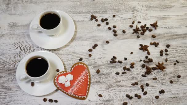 Concetto di relazioni amorose. Caffè in tazze bianche, biscotti allo zenzero fatti in casa a forma di cuore su sfondo di legno. mano mette un biscotto su un altro per fare coppia, 4K
 - Filmati, video