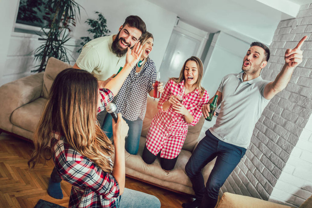 Grupo de amigos jogando karaoke em casa. Conceito sobre amizade, entretenimento doméstico e pessoas - Foto, Imagem