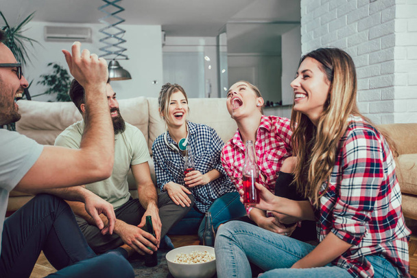 Group of happy young friends having fun and drinking beer in home interior - Photo, Image
