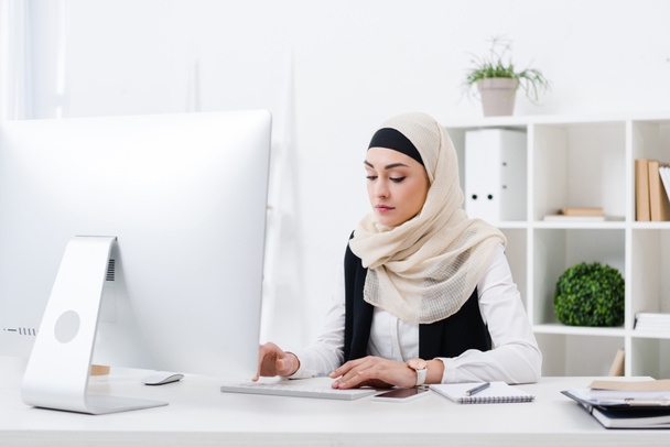 портрет сфокусированной мусульманки-предпринимательницы, работающей на компьютере в офисе
 - Фото, изображение