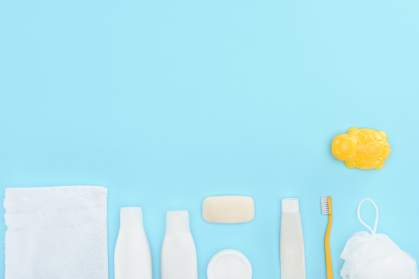 vista superior de juguete, cepillo de dientes, pasta de dientes, toalla y jabón, aislado en azul
 - Foto, imagen