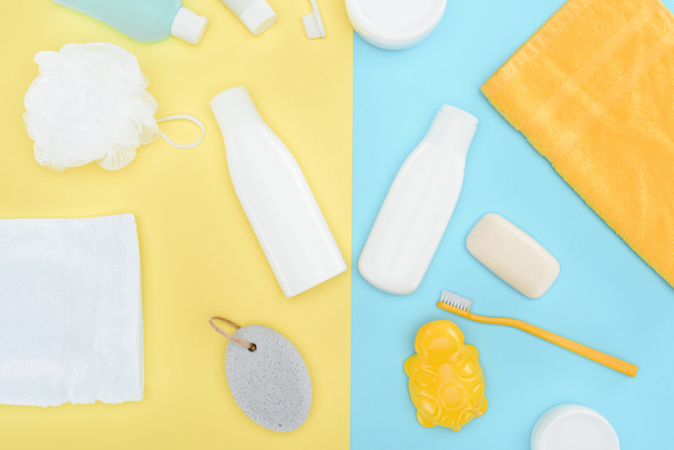 flat lay with body lotion in bottles, toothbrushes, pumice and towels, isolated on blue and yellow - Φωτογραφία, εικόνα