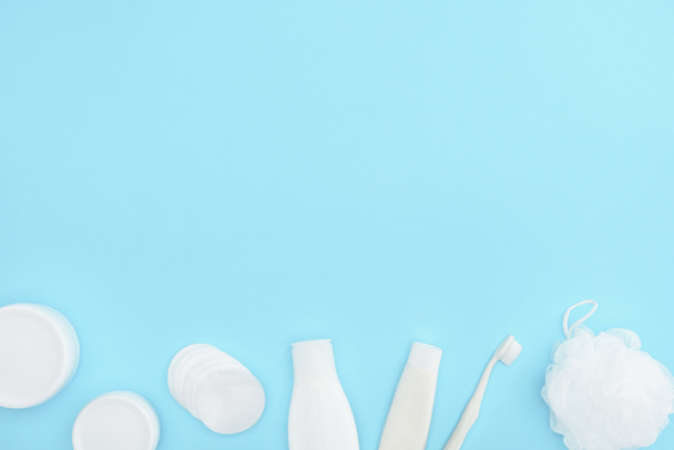 vista superior de envases y botellas de plástico con crema, esponja, pasta de dientes y cepillo de dientes, aislados en azul
 - Foto, Imagen