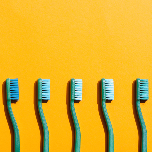 green toothbrushes in row, on yellow with copy space - Foto, Imagem