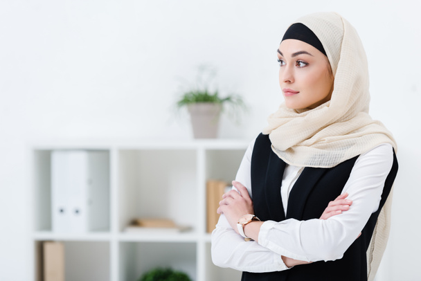 portrait of businesswoman in hijab with arms crossed standing in office - Foto, Imagen