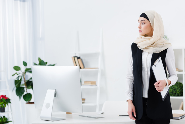 pensive arabic businesswoman with folder in hand in office - Фото, изображение