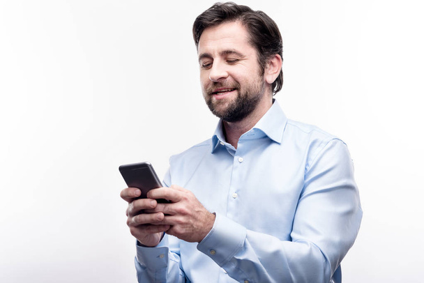 Charming man in blue shirt typing on his phone - Zdjęcie, obraz