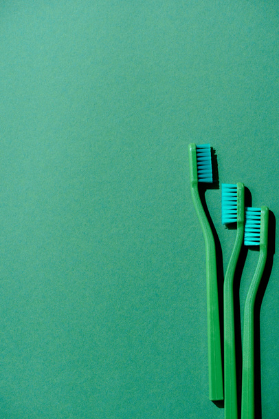 κάτοψη του πράσινου οδοντόβουρτσες, στο πράσινο με αντίγραφο χώρου - Φωτογραφία, εικόνα