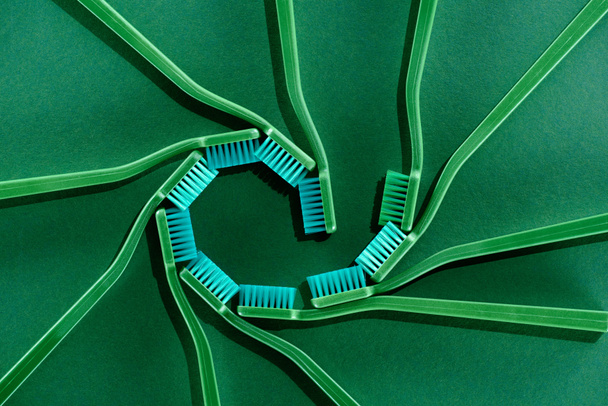 top view of spiral composition with toothbrushes on green - Valokuva, kuva