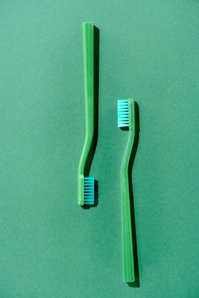bovenaanzicht van groene tandenborstels, op groen - Foto, afbeelding