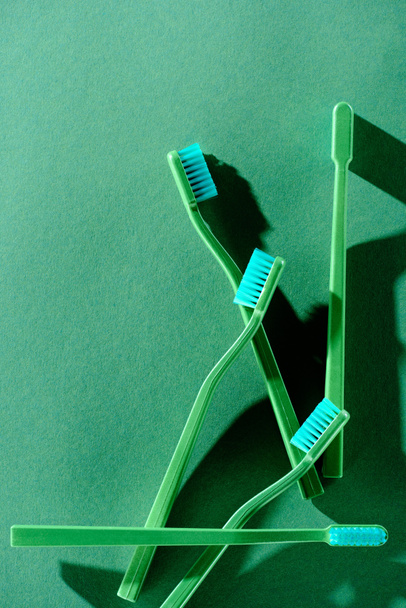 top view of green toothbrushes, on green - Fotoğraf, Görsel