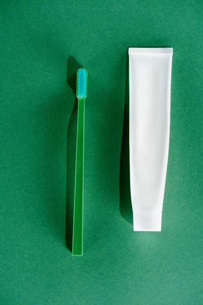bovenaanzicht van de tandenborstel en een tube tandpasta, op groen - Foto, afbeelding