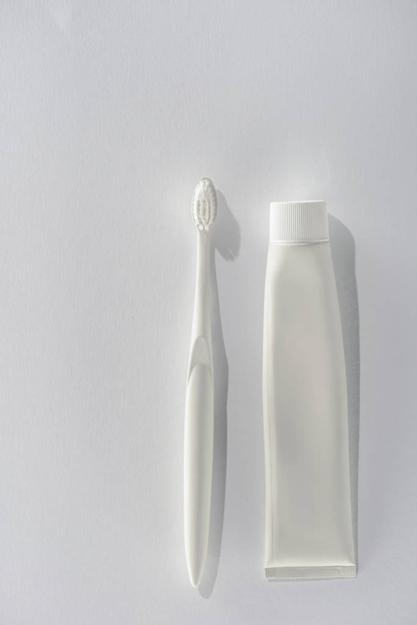 top view of white toothbrush and tube of toothpaste, on white - Foto, afbeelding