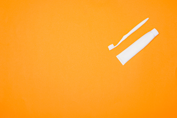 vista superior del cepillo de dientes blanco y tubo de pasta de dientes, aislado en naranja
 - Foto, Imagen