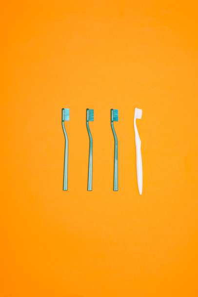 yeşil ve beyaz diş fırçaları satırda, turuncu üzerinde izole Üstten Görünüm - Fotoğraf, Görsel
