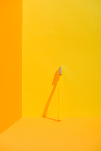 escova de dentes amarela em pé na parede laranja
 - Foto, Imagem