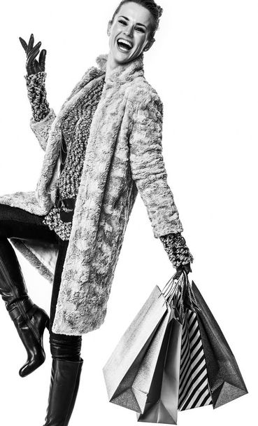 Full length portrait of smiling stylish fashion-monger in winter coat isolated on white background with shopping bags - 写真・画像