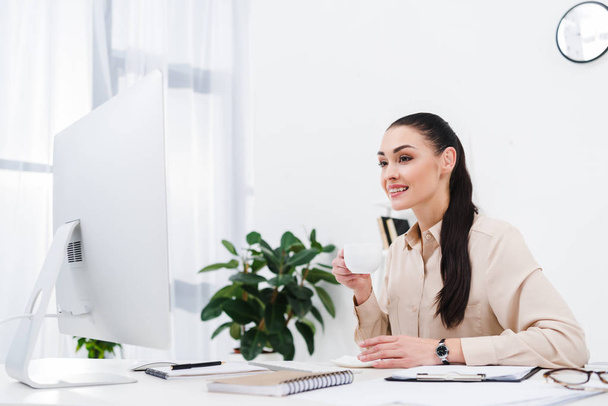 ritratto di donna d'affari sorridente con tazza di caffè sul posto di lavoro in ufficio
 - Foto, immagini