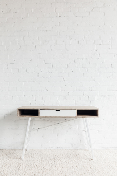 empty work table in front of white brick wall, mockup concept - Φωτογραφία, εικόνα