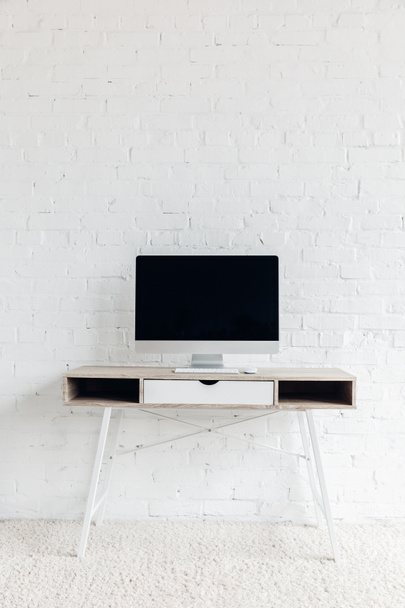 pantalla copmuter en blanco en el lugar de trabajo vacío frente a la pared de ladrillo blanco, concepto de maqueta
 - Foto, imagen