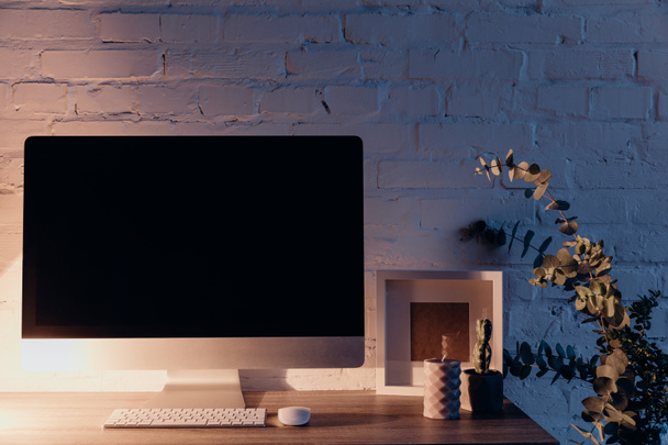 blank copmuter screen on workplace illuminated by table lamp in evening, mockup concept - Photo, Image