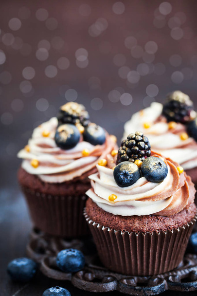 Zelfgemaakte heerlijke chocolade cupcakes met verse bessen bovenop  - Foto, afbeelding