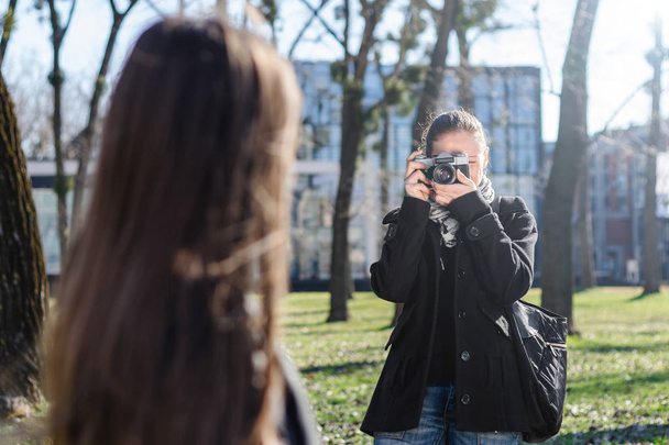 Woman taking a photo with old analog camera in spring park - Foto, imagen