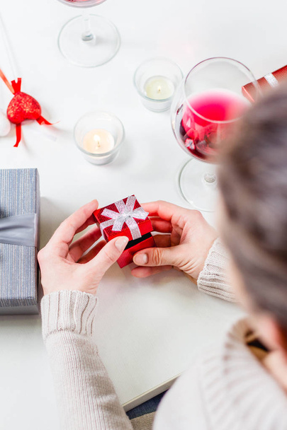 close-up of woman opening red gift box on festive table - Foto, afbeelding