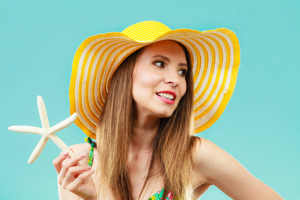Woman in yellow hat holding white shell - Zdjęcie, obraz