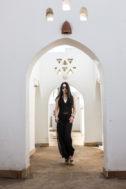 girl in sunglasses looking at camera while walking at white building in Egypt  - Photo, Image