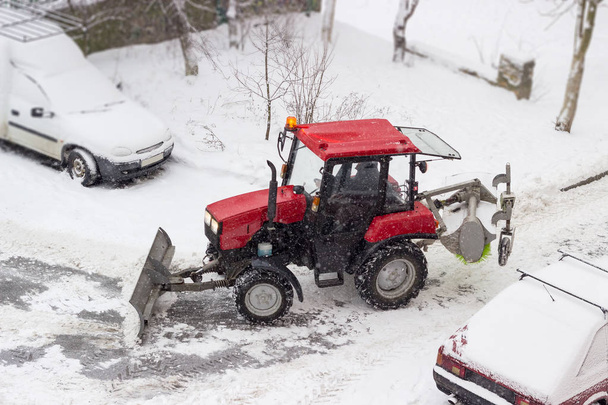 Kleiner Traktor-Schneepflug bei Schneefall im Hof - Foto, Bild