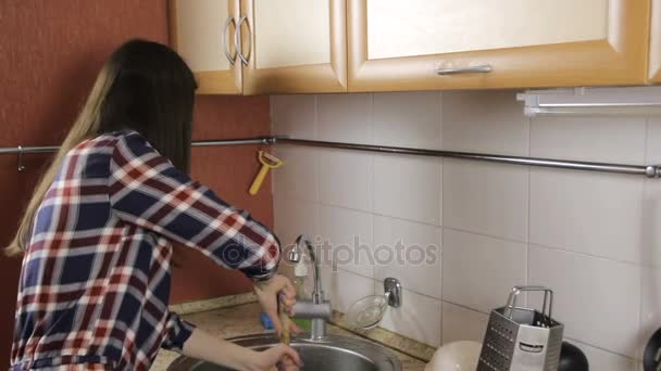 Brunette with long hair in a plaid shirt clears congestion in the sink with the plunger. - Video