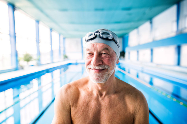Senior man standing in an indoor swimming pool. - Photo, Image