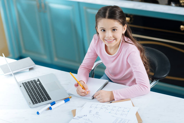Inspired girl doing her homework and smiling - Fotografie, Obrázek