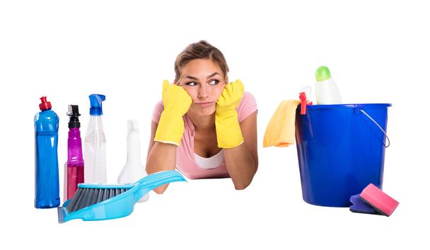 Close-up di un giovane inserviente donna sdraiato su sfondo bianco vicino ai prodotti per la pulizia
 - Foto, immagini