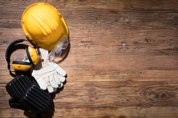 Close-up Of Yellow Hard Hat With Safety Equipment On Wooden Background - Φωτογραφία, εικόνα