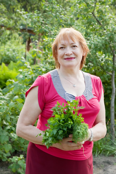Mature woman with dill and parsley - Фото, зображення