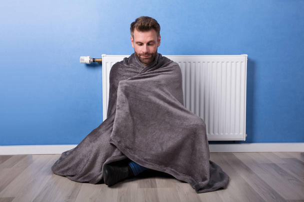 Young Man Wrapped In Blanket Sitting In Front Of Heater At Home - Photo, image