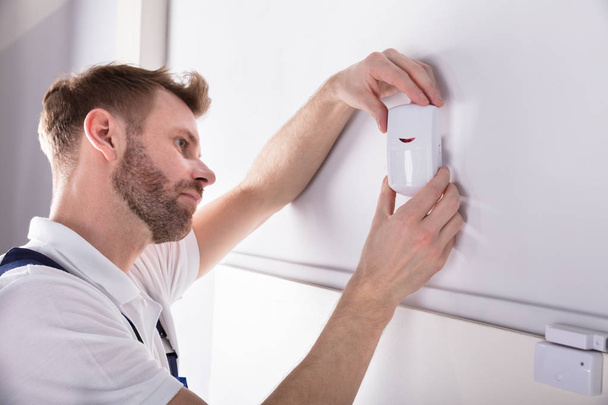 Close-up Of Young Male Electrician Installing Security System Door Sensor On Wall - Fotoğraf, Görsel