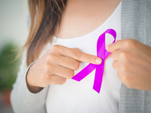 Mains de femme tenant un ruban de sensibilisation au CANCER violet. Campagne de sensibilisation au cancer
 - Photo, image