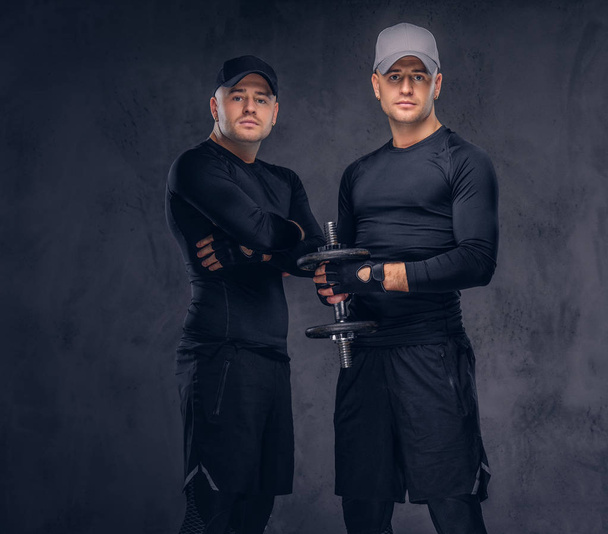 Portrait of two handsome young male dressed in a black sportswea - Фото, изображение