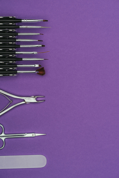 vista superior de la fila de herramientas de manicura aisladas en púrpura
 - Foto, imagen