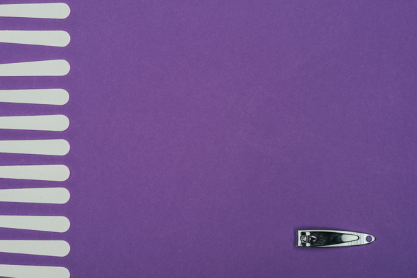 Ansicht von Nagelzangen und Nagelfeilen isoliert auf lila - Foto, Bild